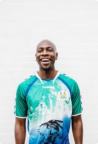 Smiling bald man in a colorful shirt, white wall behind.