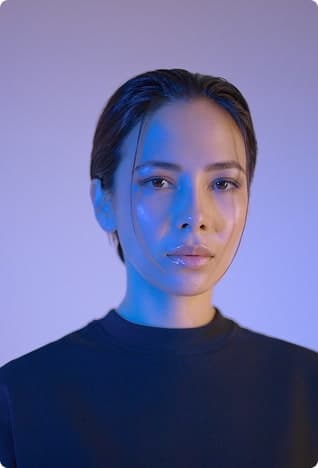 Person in cool blue-purple lighting with a neutral expression.